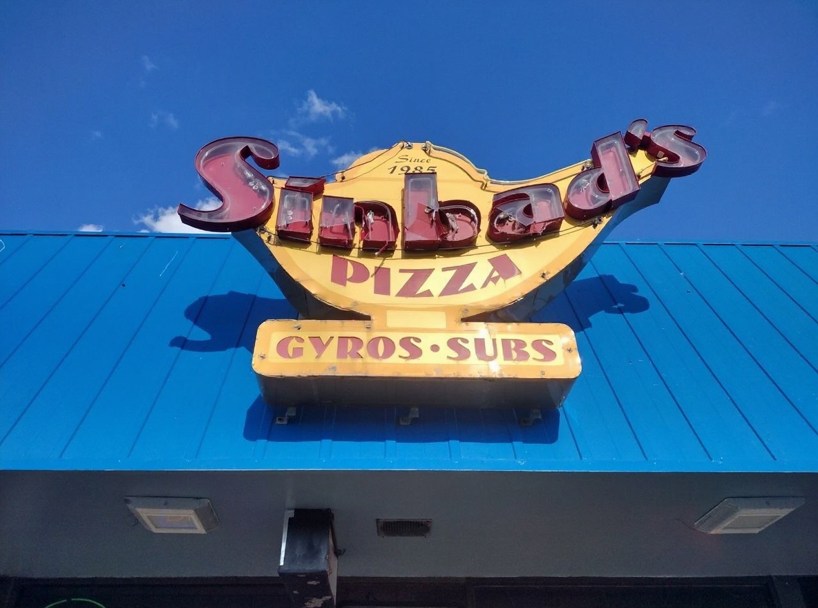 Sinbad's iconic genie-lamp roof sign in Ocean City, MD — gold lamp, cursive red 'Sinbad's', Since 1985, Pizza · Gyros · Subs