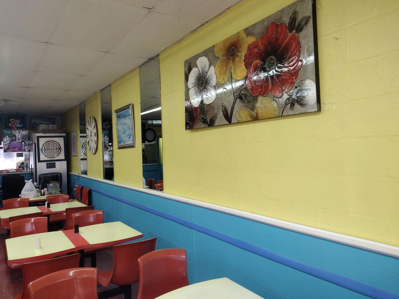 Inside Sinbad's dining room — yellow walls, red molded chairs, blue wainscot and floral artwork